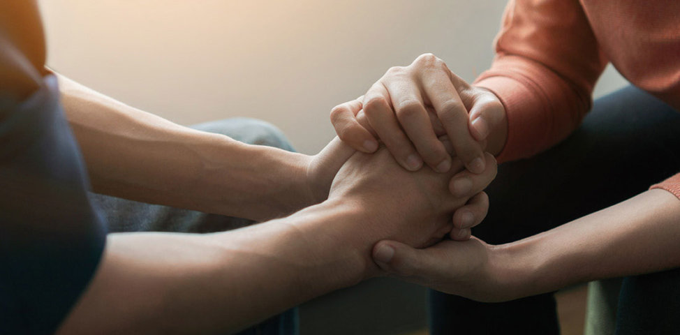 Therapist and patient hold hands during adoption-competent therapy session