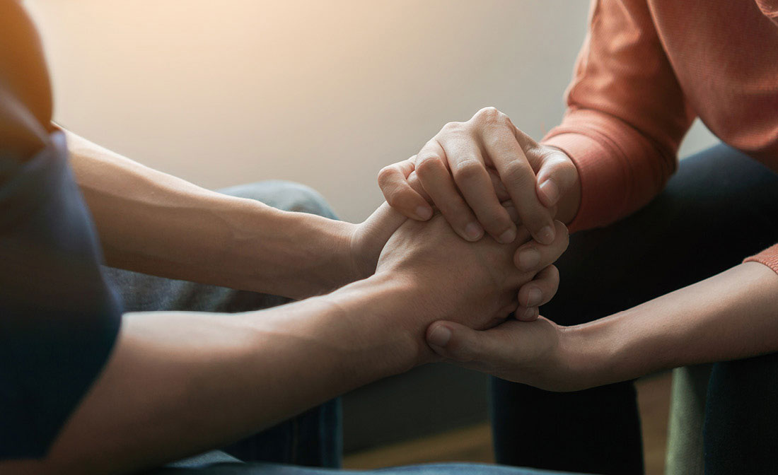 Therapist and patient hold hands during adoption-competent therapy session