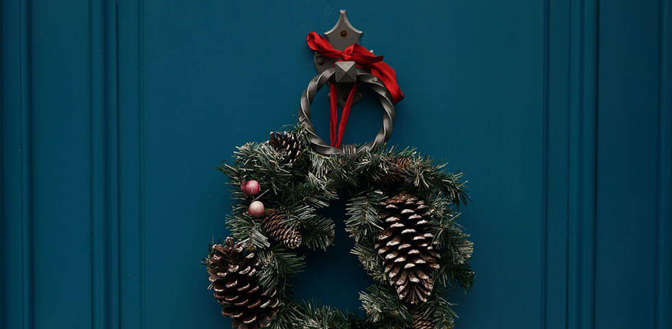Christmas wreath hanging on a blue door.