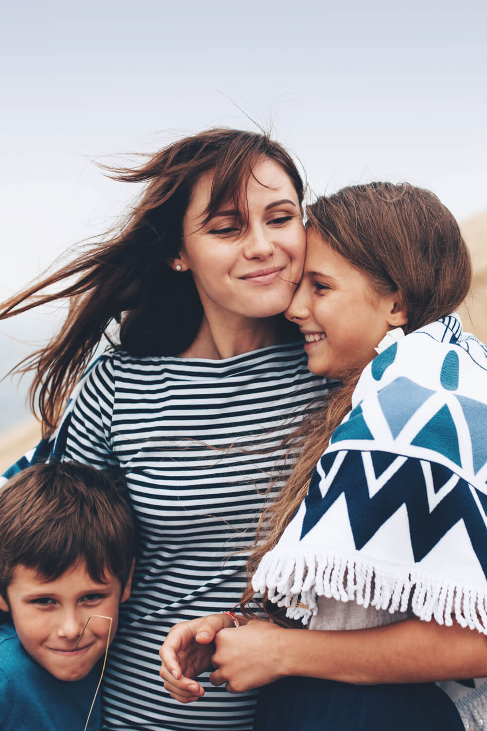 Single mom hugs son and daughter.