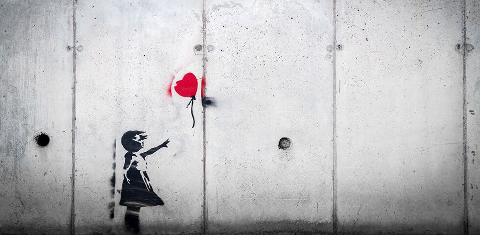 Girl painted on a wall holding heart shaped balloon.