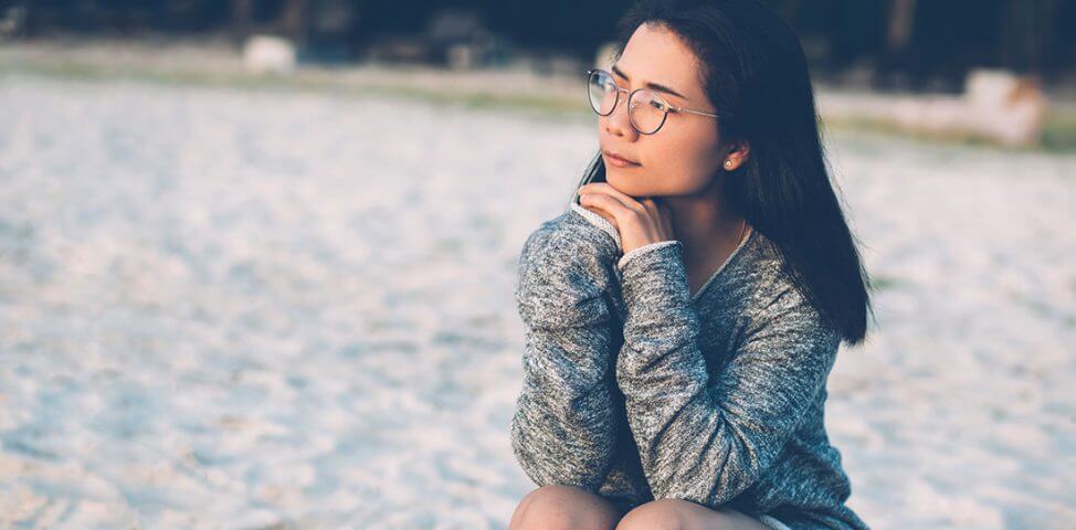 Woman sits on the beach.