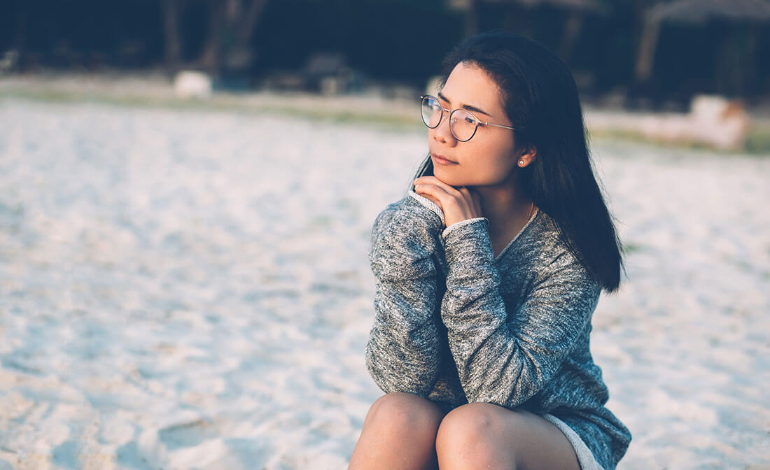 Woman sits on the beach.