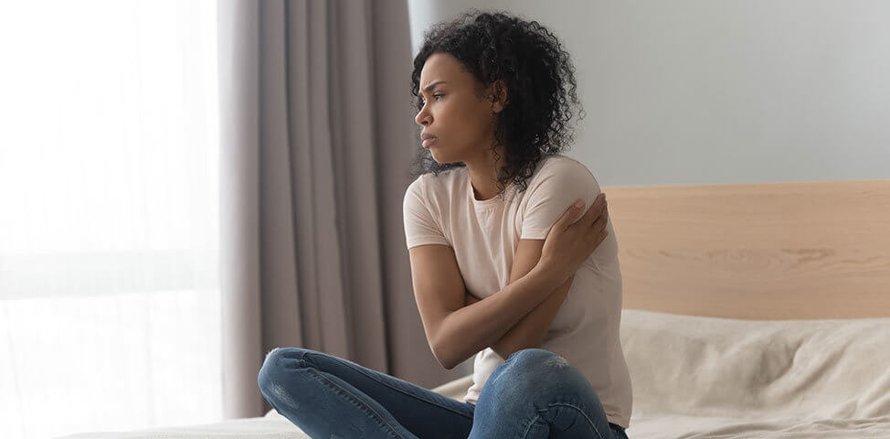 Grieving woman sits on a bed.